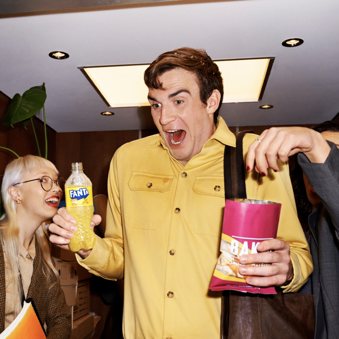 Chico alegre con botella de Fanta y bolsa de aperitivos