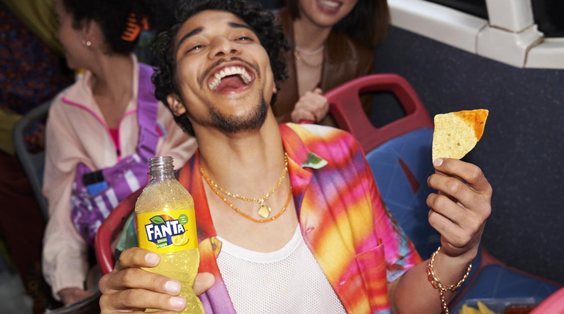 Man drinking fanta and eating nachos