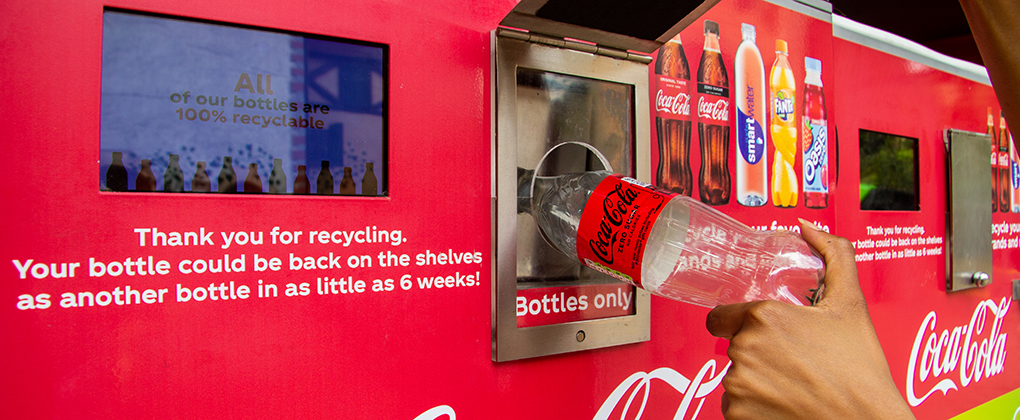 coca-cola bottle being recycled at a special receptacle 