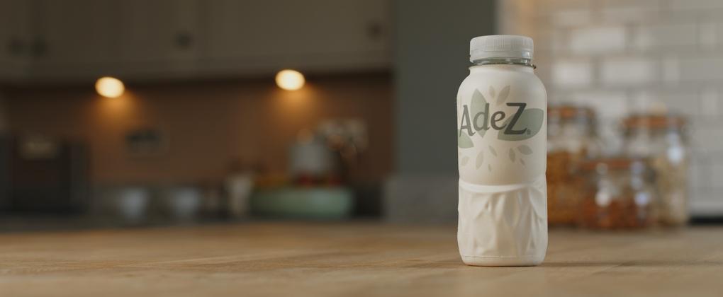A front view of the AdeZ paper bottle on top of a counter top in a kitchen scenario