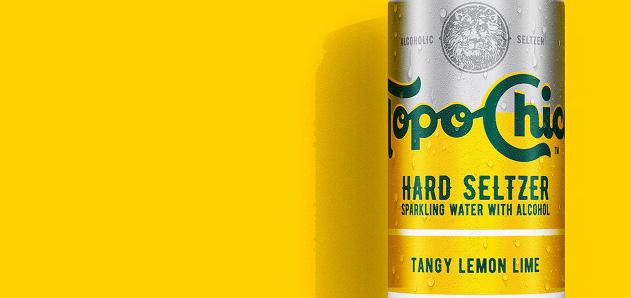 Topo Chico Hard Seltzer can on yellow background.