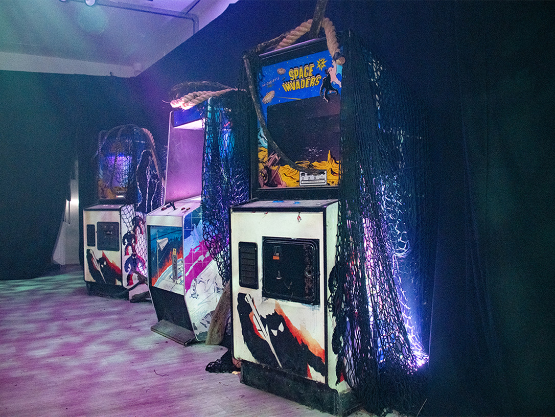 View of Coca-Cola X Stranger Things Arcade interior with three arcade machines covered with different types of fabrics 