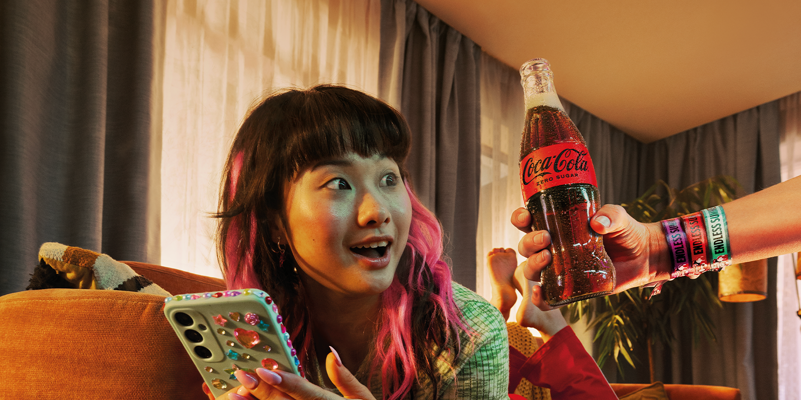 teenager scrolling on her phone looking at a glass bottle of coca-cola zero surgar