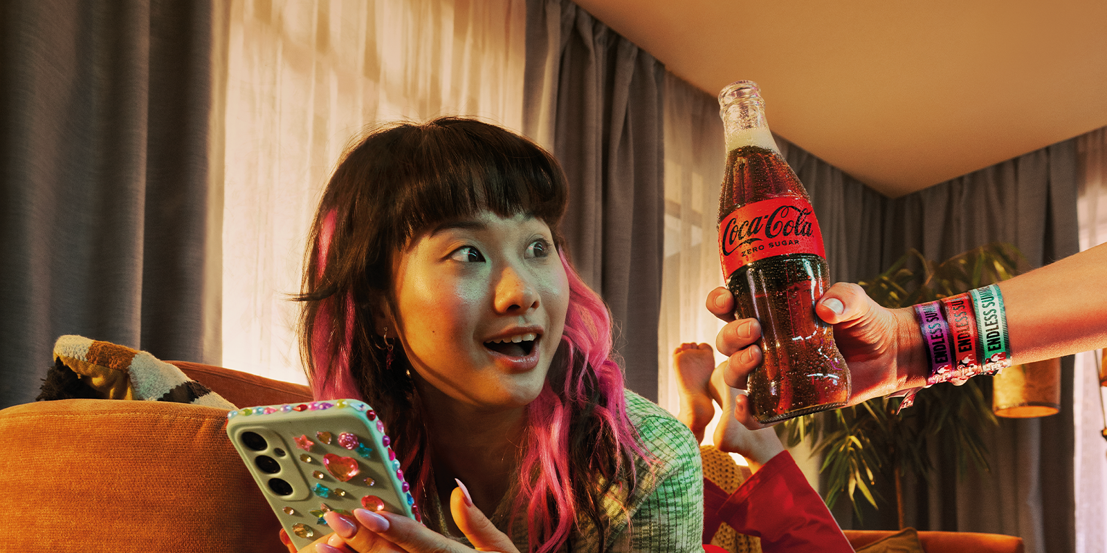 teenager scrolling on her phone looking at a glass bottle of coca-cola zero sugar