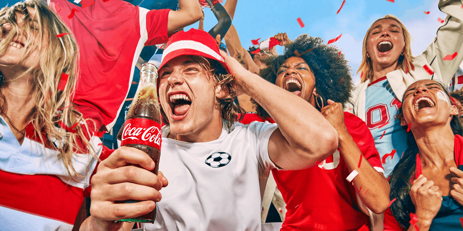 Image of football fans celebrating with a bottle of Coca-Cola
