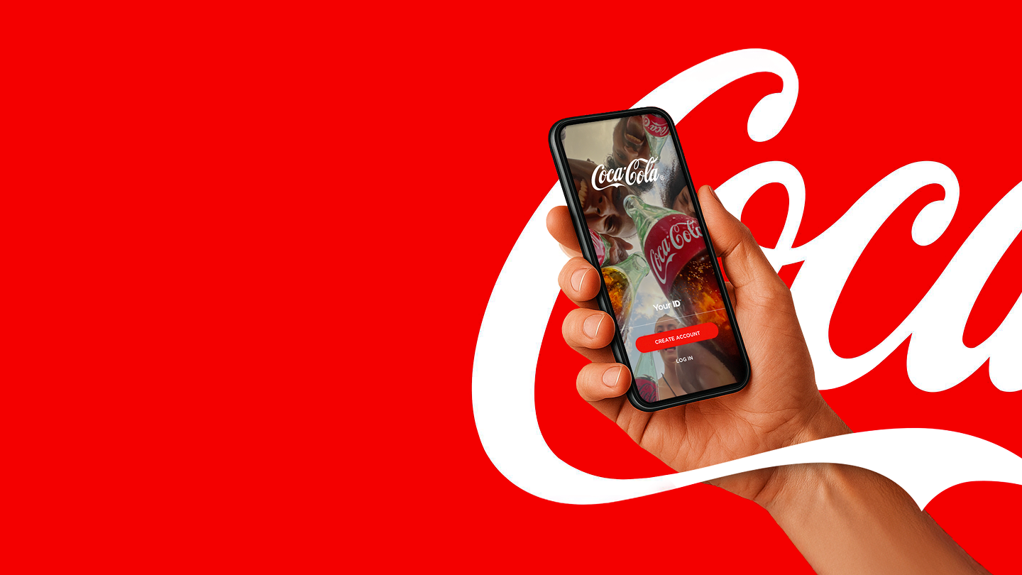 A hand holds a smartphone with the Coca-Cola app against a red background.