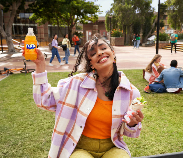 Woman with bottle of Fanta and fruit on cocktail stick