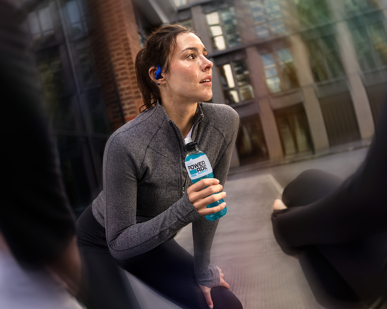 Eine Frau in Sportkleidung hält eine Powerade-Flasche.