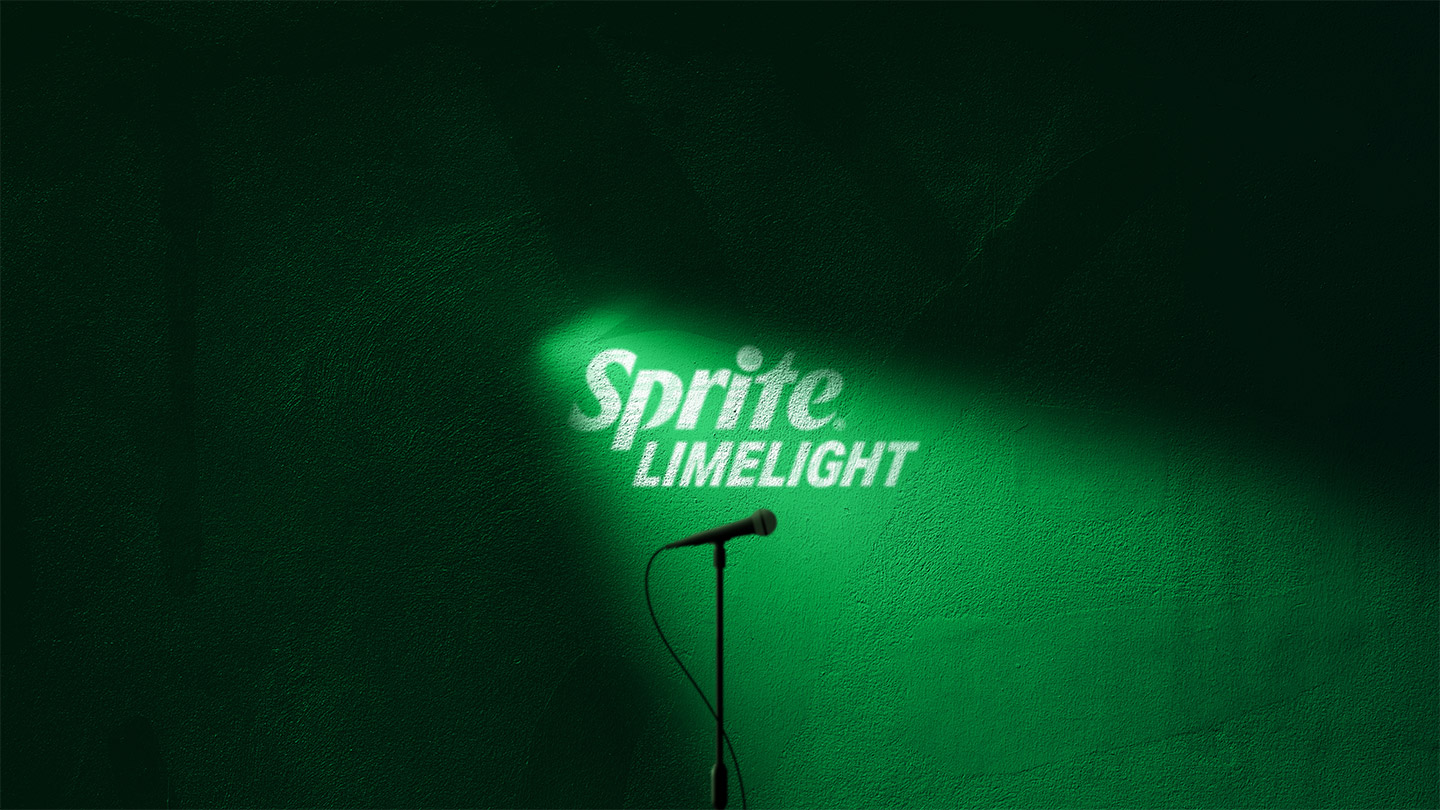 Reflector iluminando una pared verde con la frase: Sprite limelight. Acompañado de la silueta de un micrófono. 