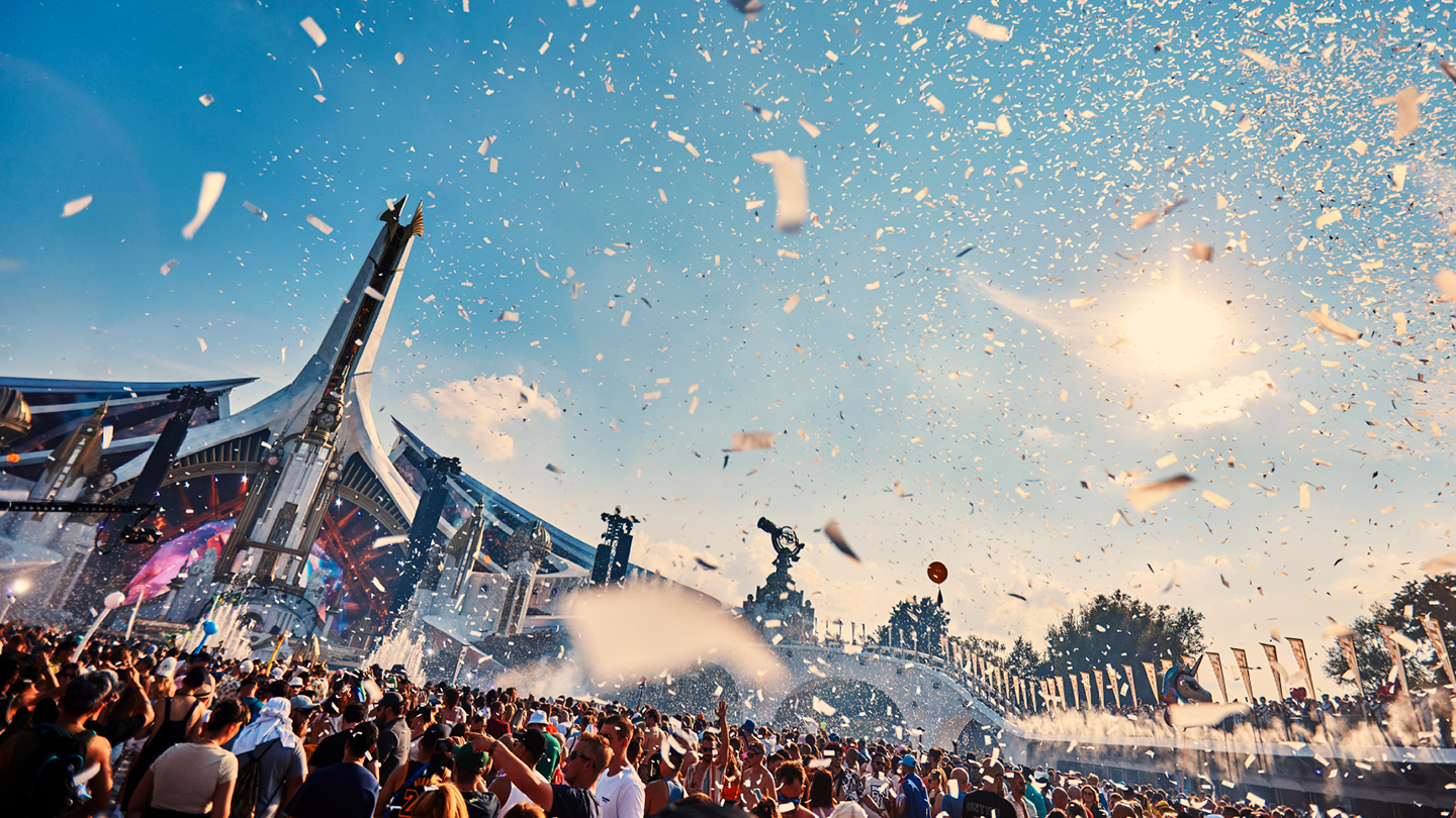 Πλήθος κόσμου σε ένα μουσικό φεστιβάλ με κομφετί στον αέρα.