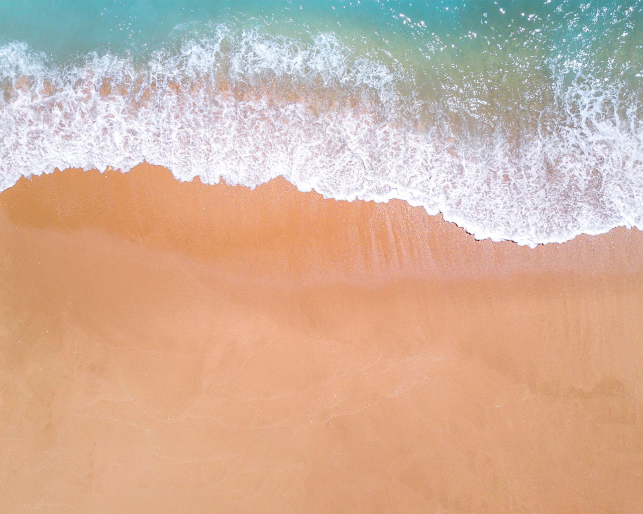 Top view of a wave breaking onto the sand