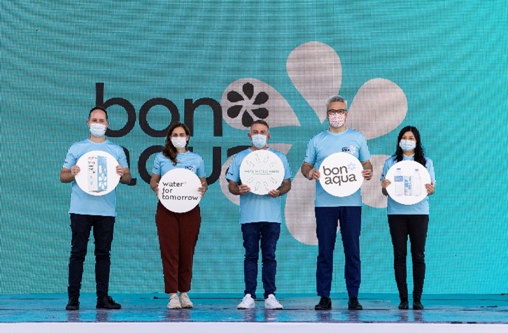 A group of people wearing blue t-shirts holding Bon Aqua signs