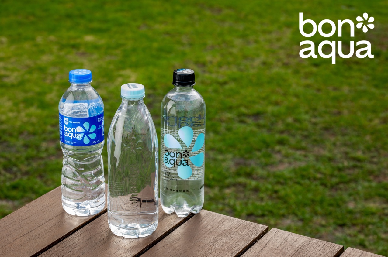 Three Bon Aqua bottles on top of a wooden table on an open-air environment