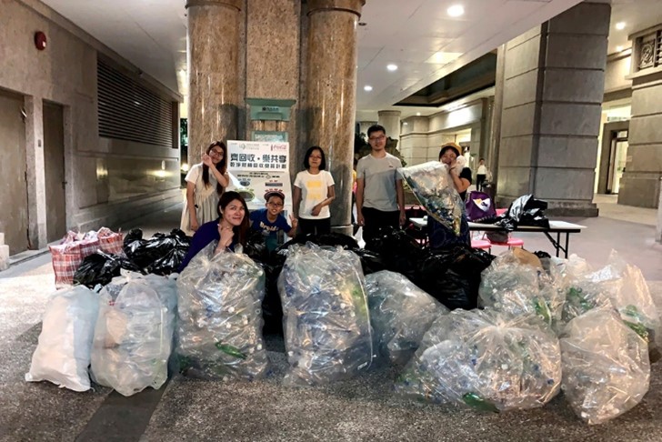 A group of people displaying bags of collected plastic waste 