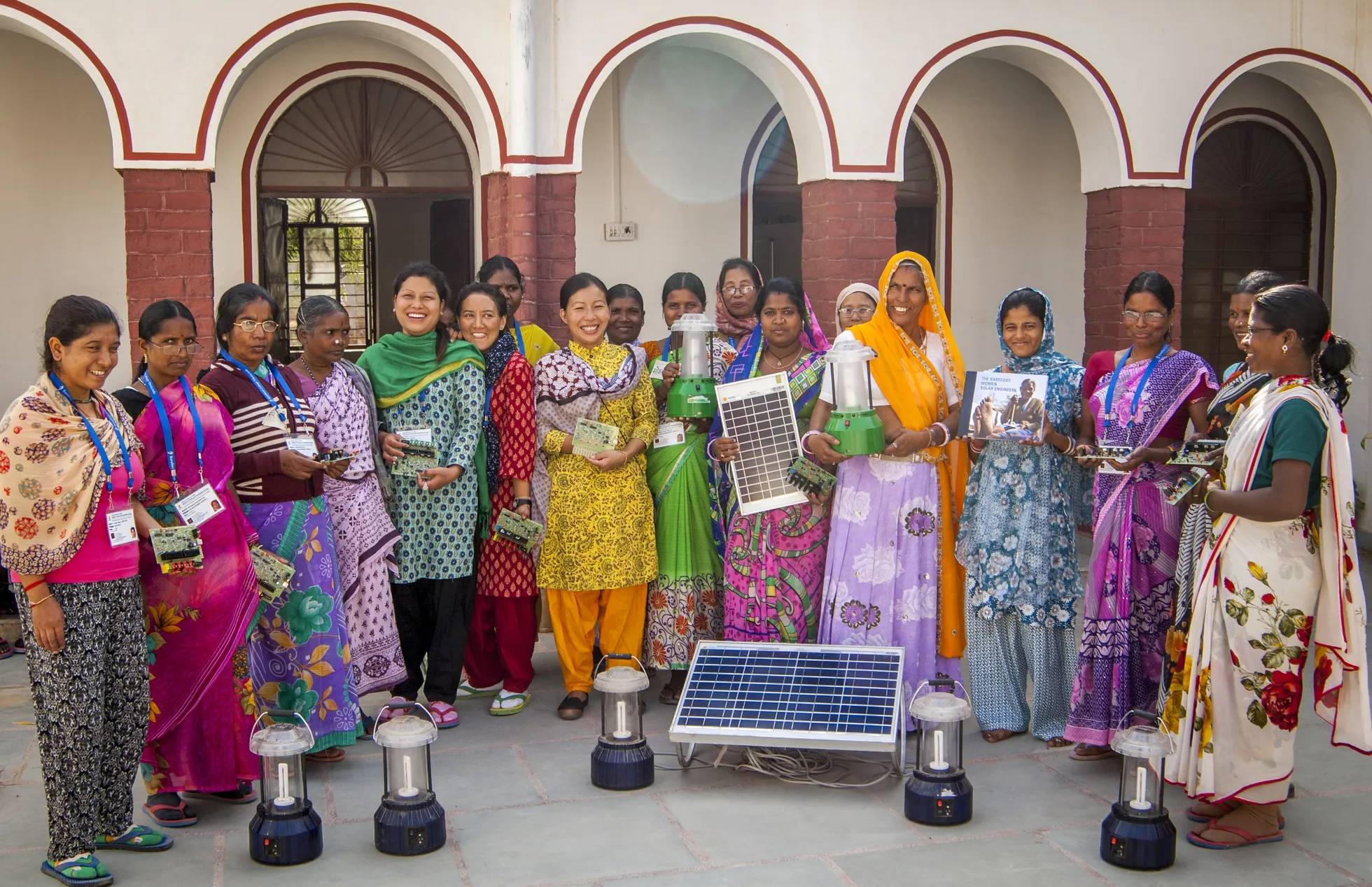 Group of women displaying solar cell panels, small circuits and electric lamps.
