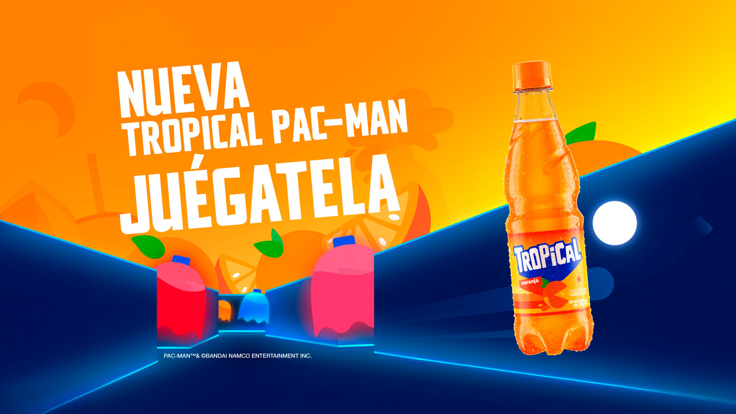 Botella de la nueva Tropical PAC-MAN naranja siendo perseguida por fantasmas de colores del juego PAC-MAN en un laberinto azul con cielo naranja y gajos de naranja flotando. Por encima, un texto que dice “Nueva Tropical Pac-Man, Juégatela”, junto a los logotipos de Tropical y PAC-MAN