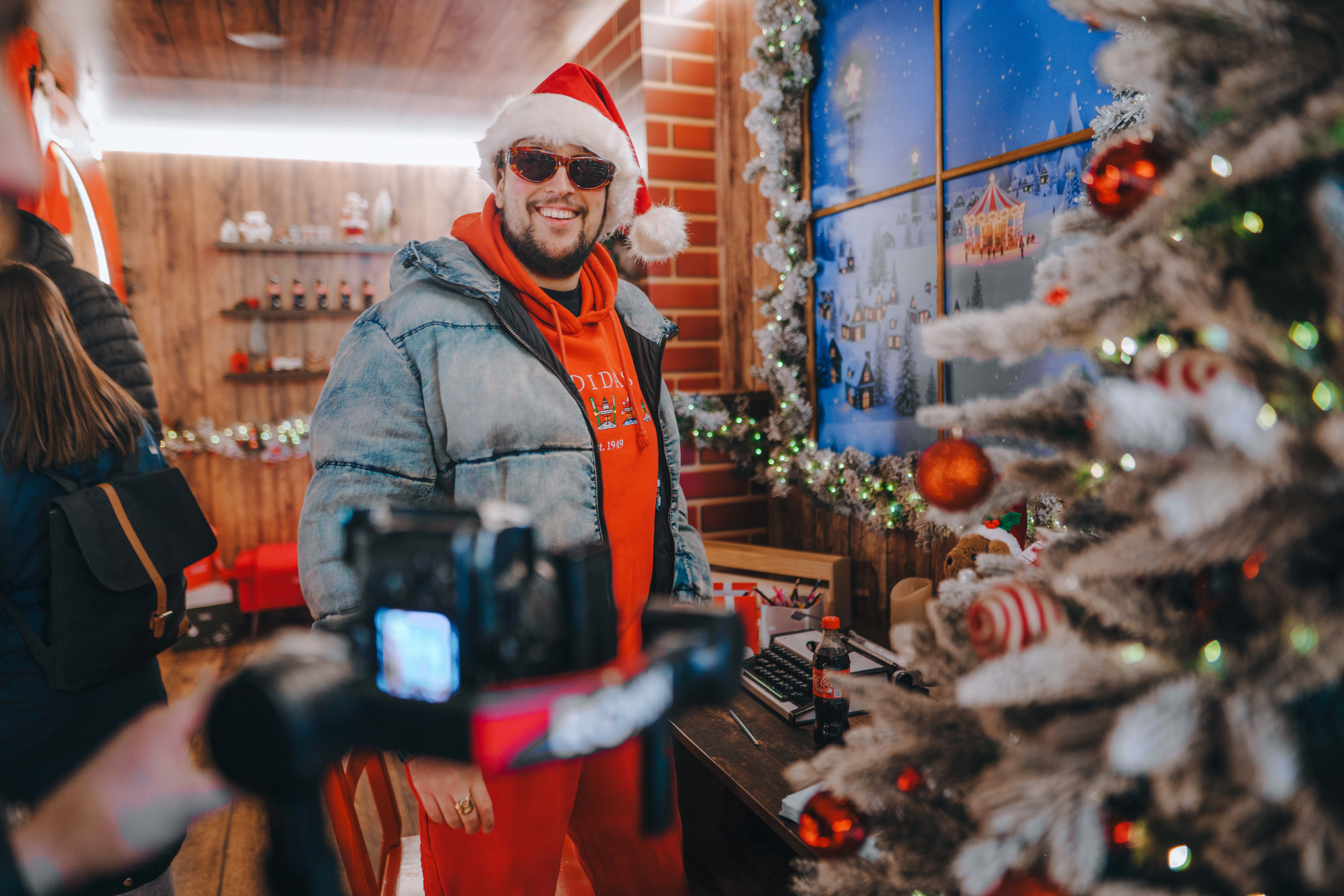Blagdanski uređeni interijer s božićnim drvcem i dekoracijama, tijekom snimanja sadržaja u sklopu adventskog događanja uz Coca‑Cola božićni kamion