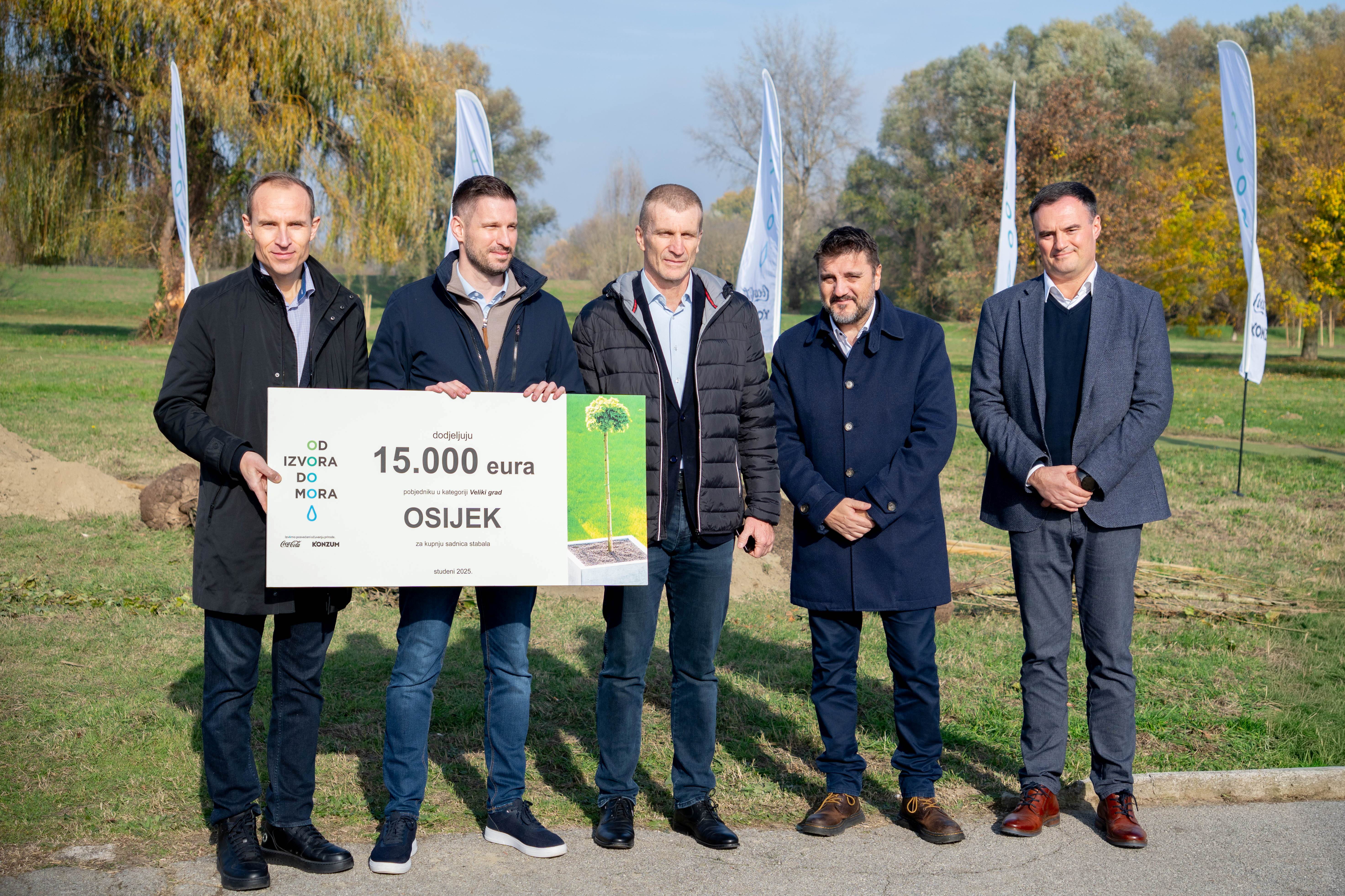 Oznaka s porukom o ozelenjivanju gradova pričvršćena na tek posađeno stablo u urbanom zelenom prostoru