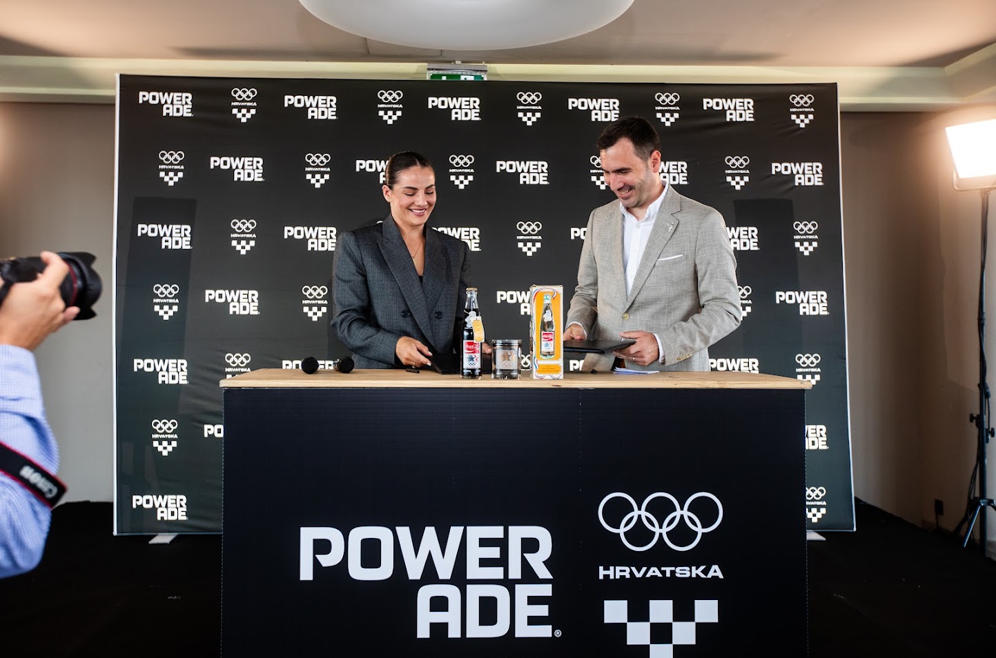 Potpisivanje sponzorskog ugovora između predstavnika Coca‑Cole i Hrvatskog olimpijskog odbora na događanju brenda POWERADE, uz službenu prezentaciju partnerstva.