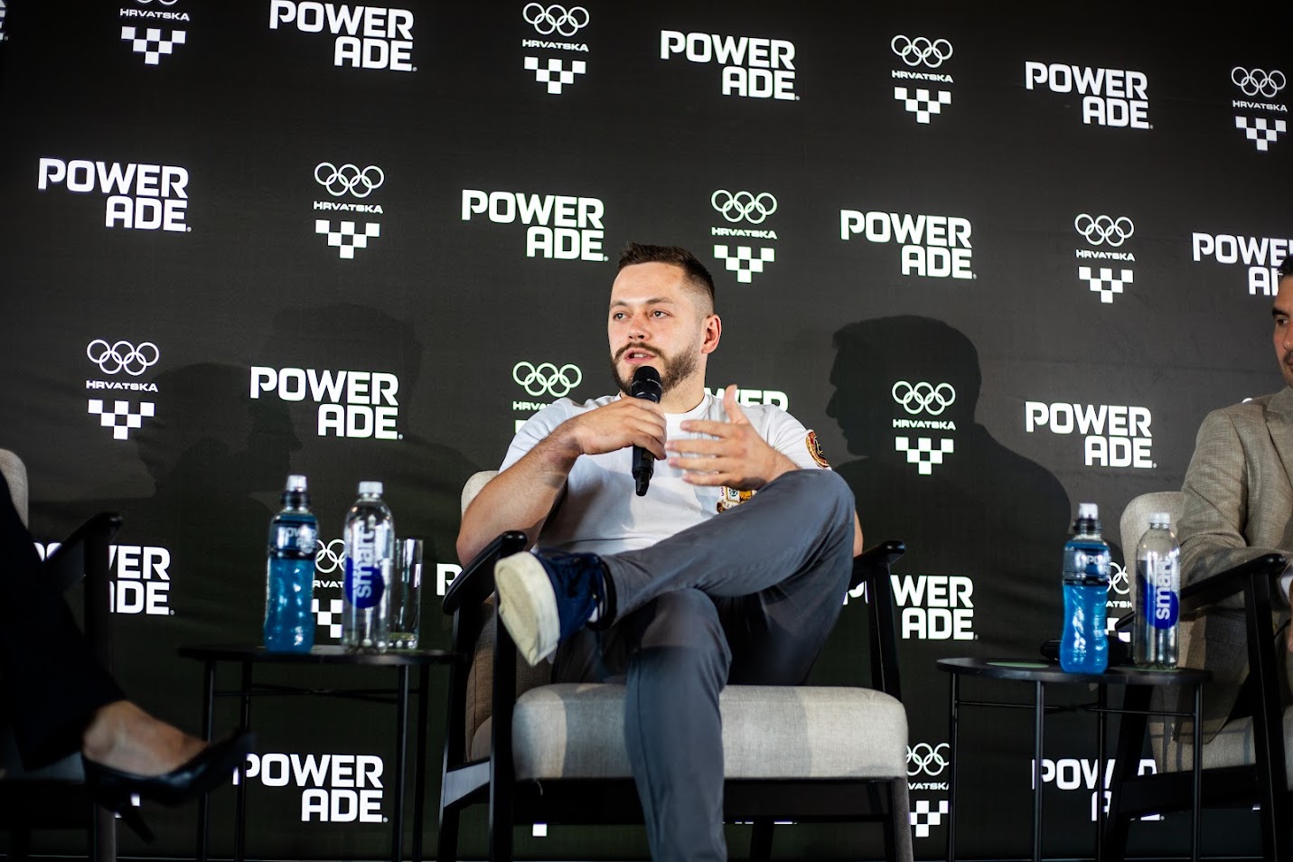 Sudionik panel rasprave govori o mentalnom zdravlju sportaša tijekom događanja inicijative POWERADE The Athletes Code, uz brendiranu pozadinu i sportsku atmosferu.