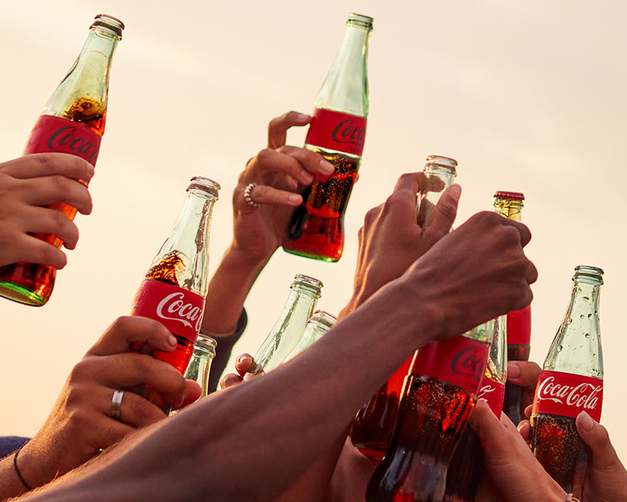 Coca-Cola üvegek a magasba tartva