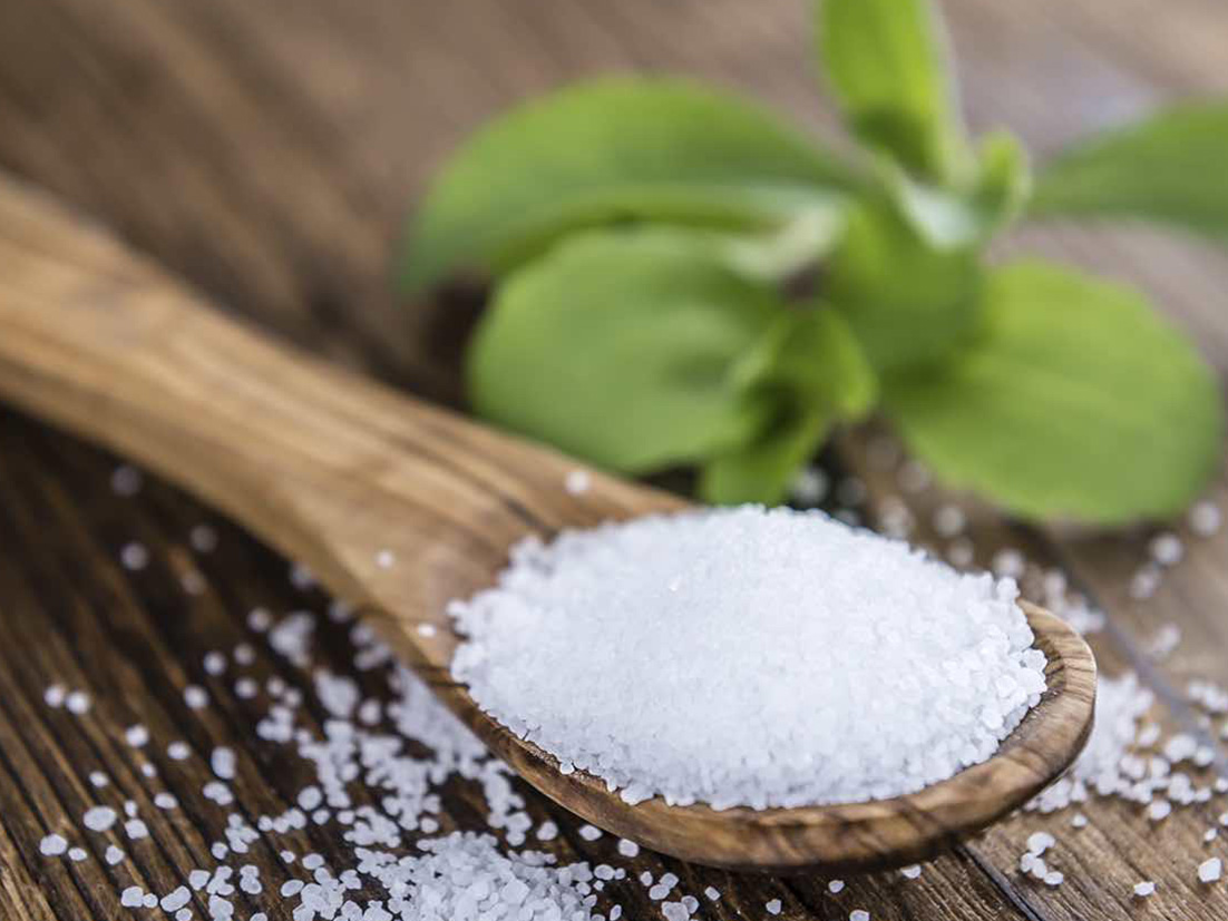 Spoon full of stevia on top of wooden table