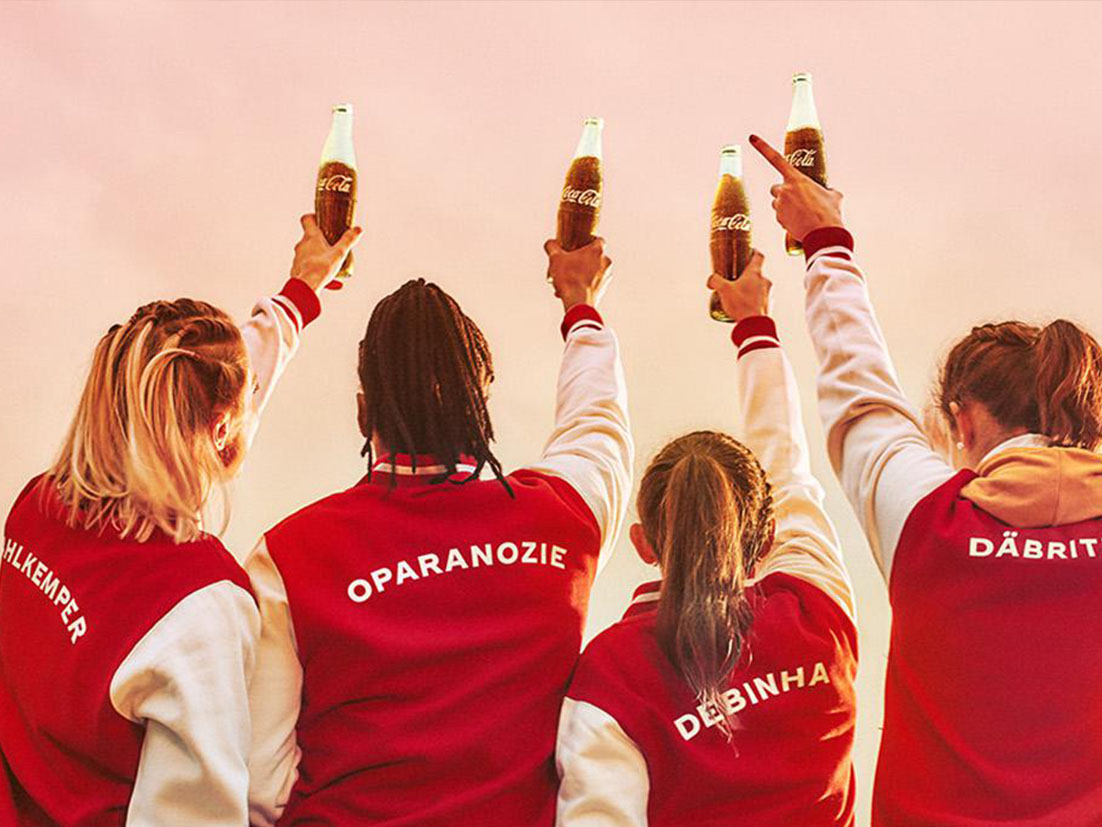 Six women with red jackets holding Coca-Cola bottles