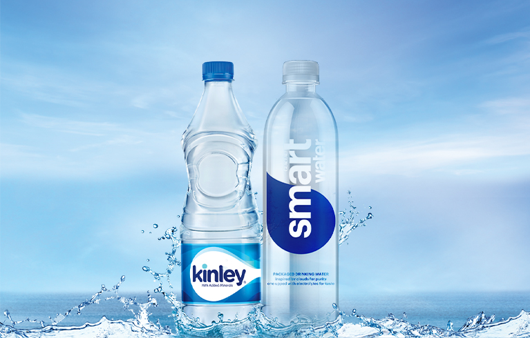 A bottle of Kinley water and Smartwater stood next to one another, resting in water