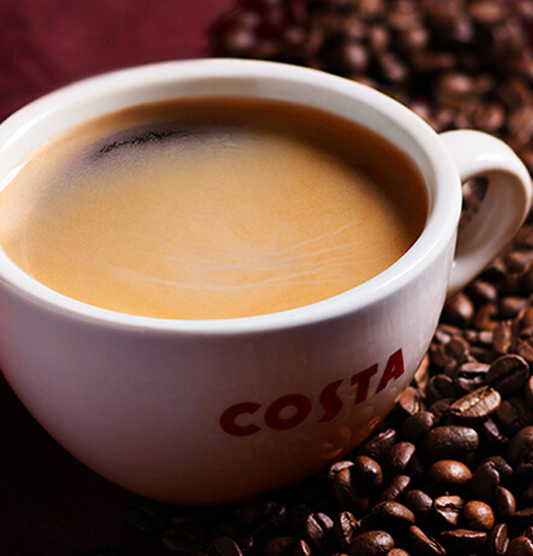 कोस्टा कॉफी का मग कॉफी बीन्स में रखा हुआ है