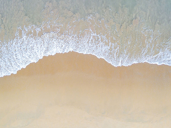 समुद्र तट की रेत पर लहरें आ रही हैं