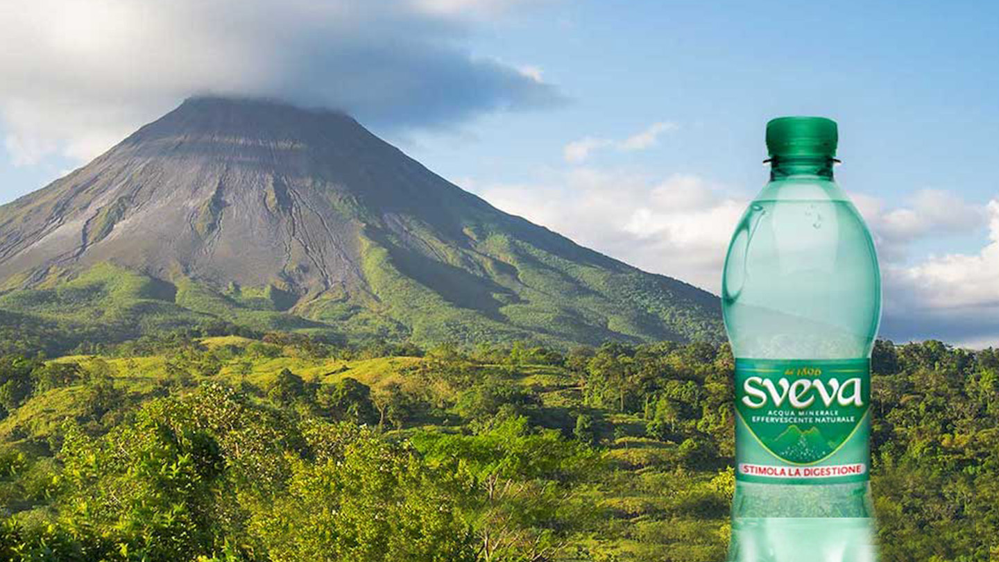 Una bottiglia di acqua Sveva con un vulcano sullo sfondo.