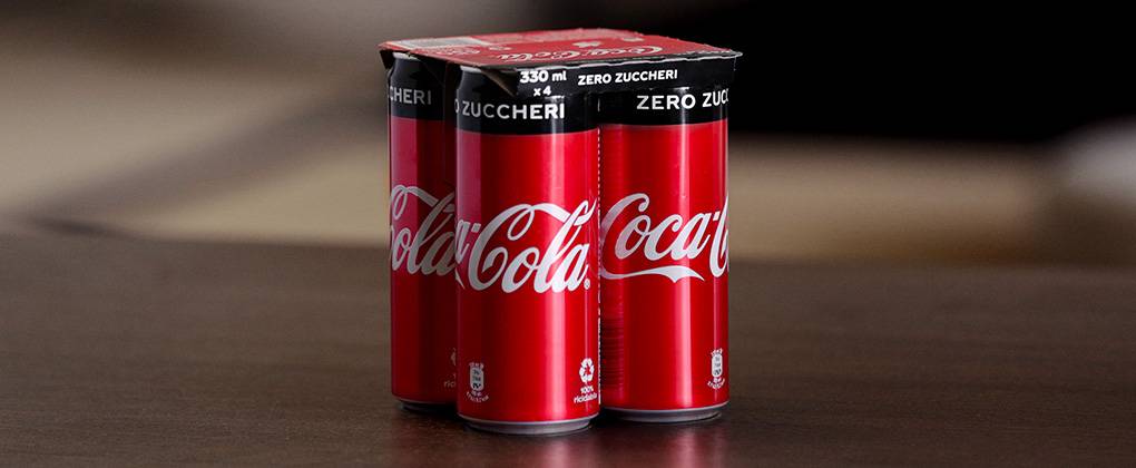 Quattro lattine di Coca-Cola Zero Zuccheri con nuovo packaging in cartone.