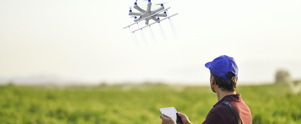 Uomo che comanda un drone facendolo volare sopra un campo.