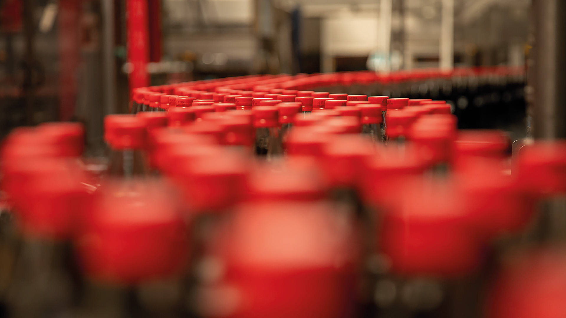 Bottiglie di Coca-Cola con tappi rossi in produzione