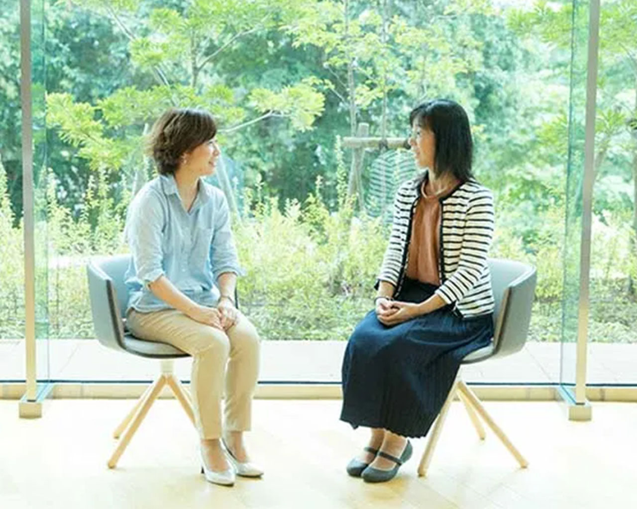 椅子に座り向かい合って緑茶飲料誕生秘話を話す古池恵美さんと長安真智子さん