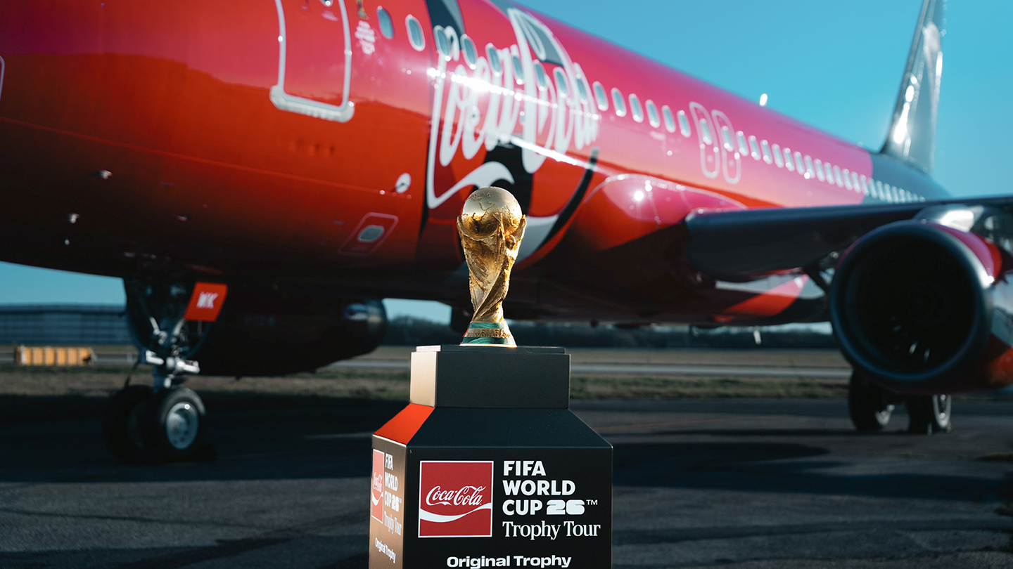 코카-콜라 전세기를 배경으로 FIFA 월드컵 오리지널 트로피가 놓여있는 모습