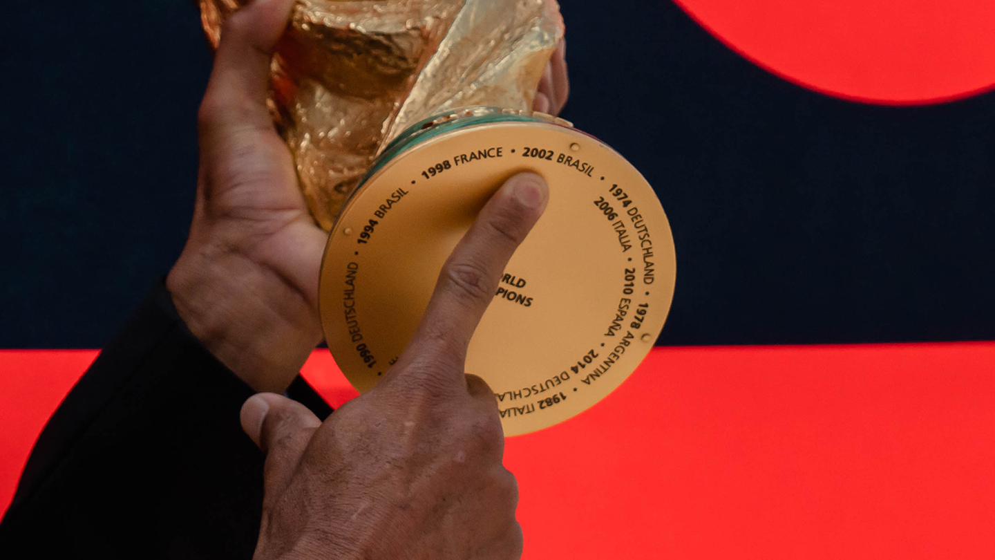 오리지널 트로피 바닥에 새겨진 우승국의 이름과 연도를 가리키고 있는 모습