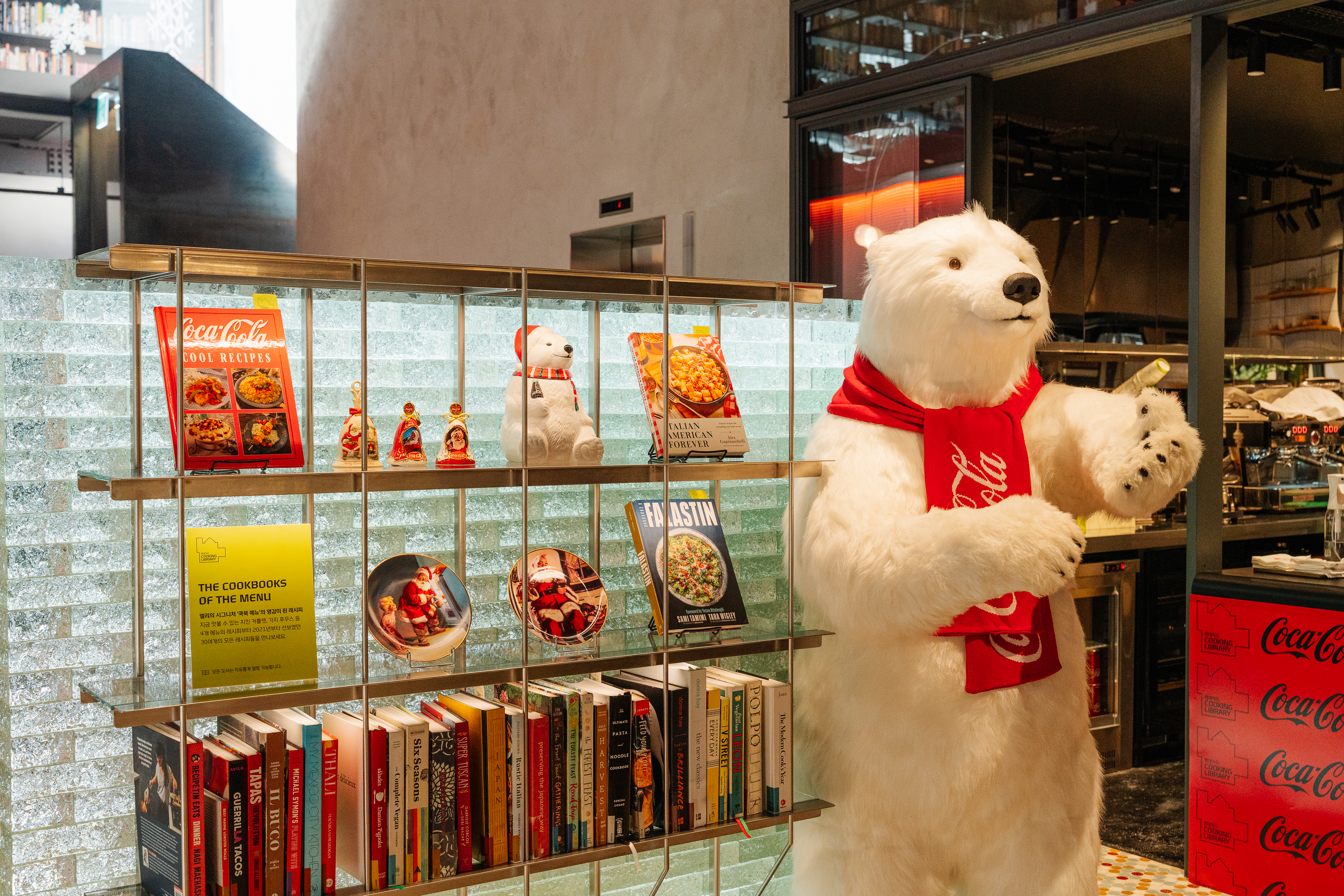 코카-콜라 레시피북이 진열된 진열장과 그 앞에서 손님들을 맞이하고 있는 폴라베어의 모습