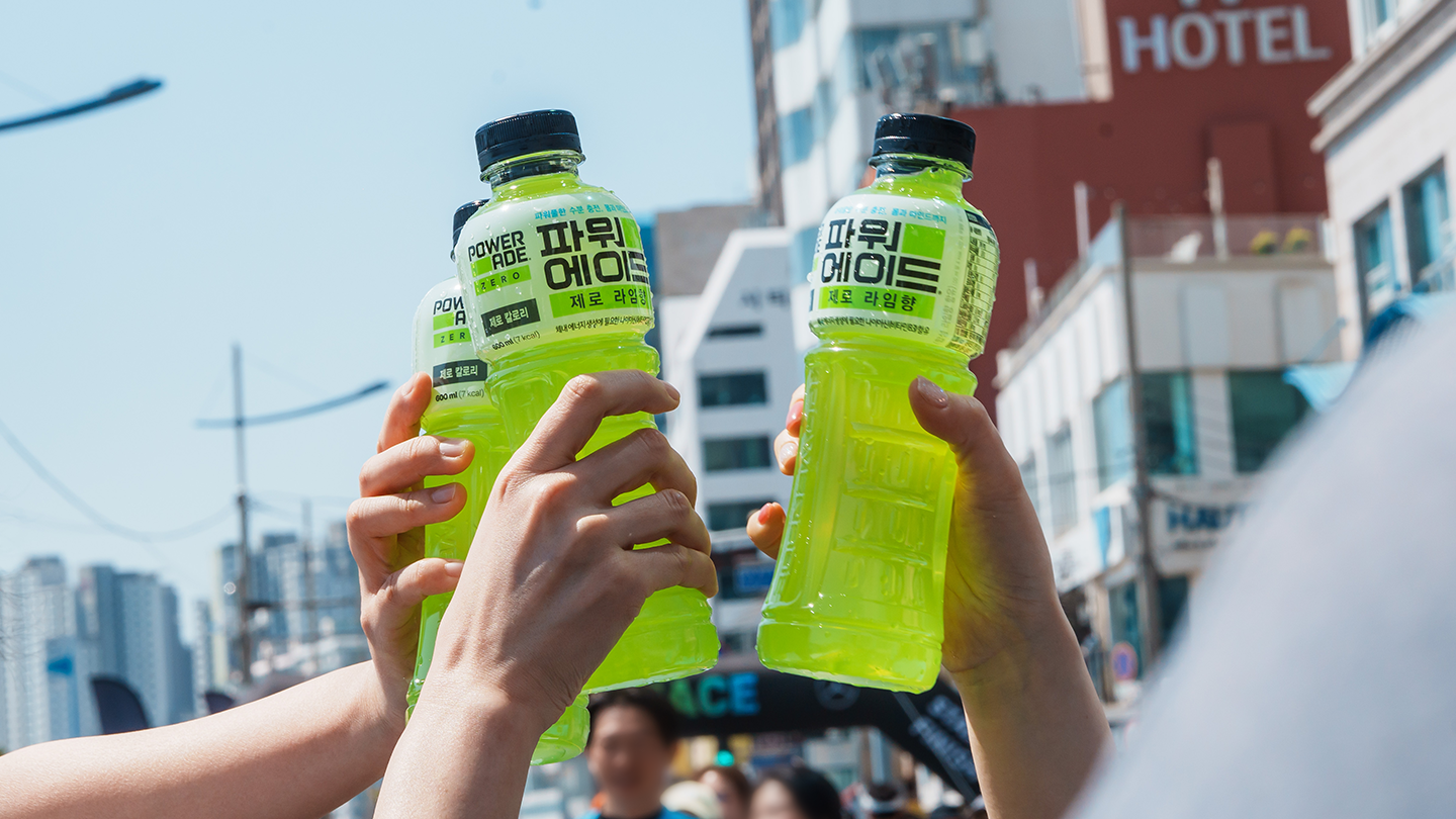 마라톤 대회에 참가한 러너들이 수분 보충을 위해 파워에이드 보틀을 맞대고 치켜드는 모습