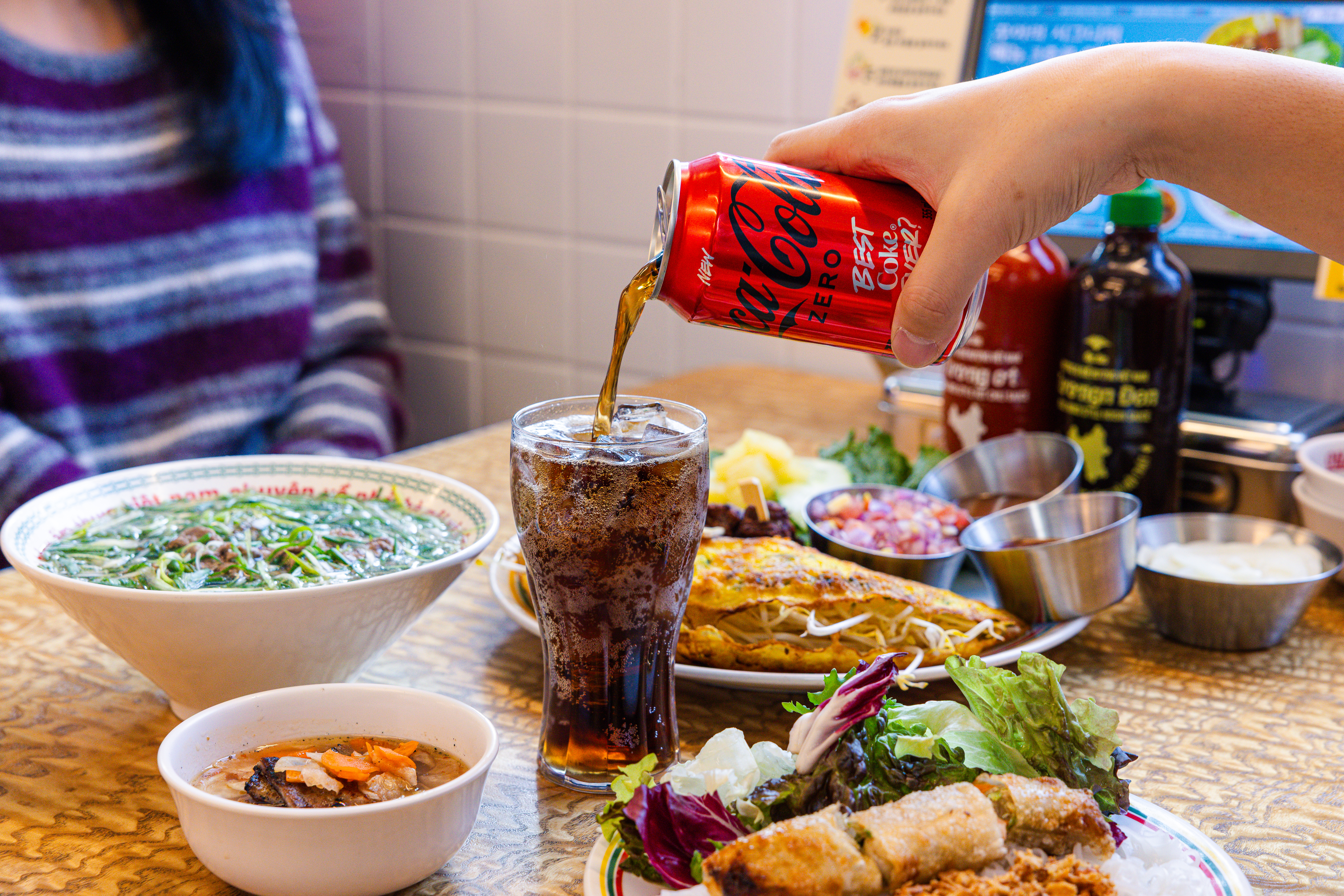 '꾸아 성수본점'의 대표메뉴, 한우사골직화칼국수, 1인 분짜, 냐짱반세오를 코카-콜라 제로와 함께 즐기고 있다.