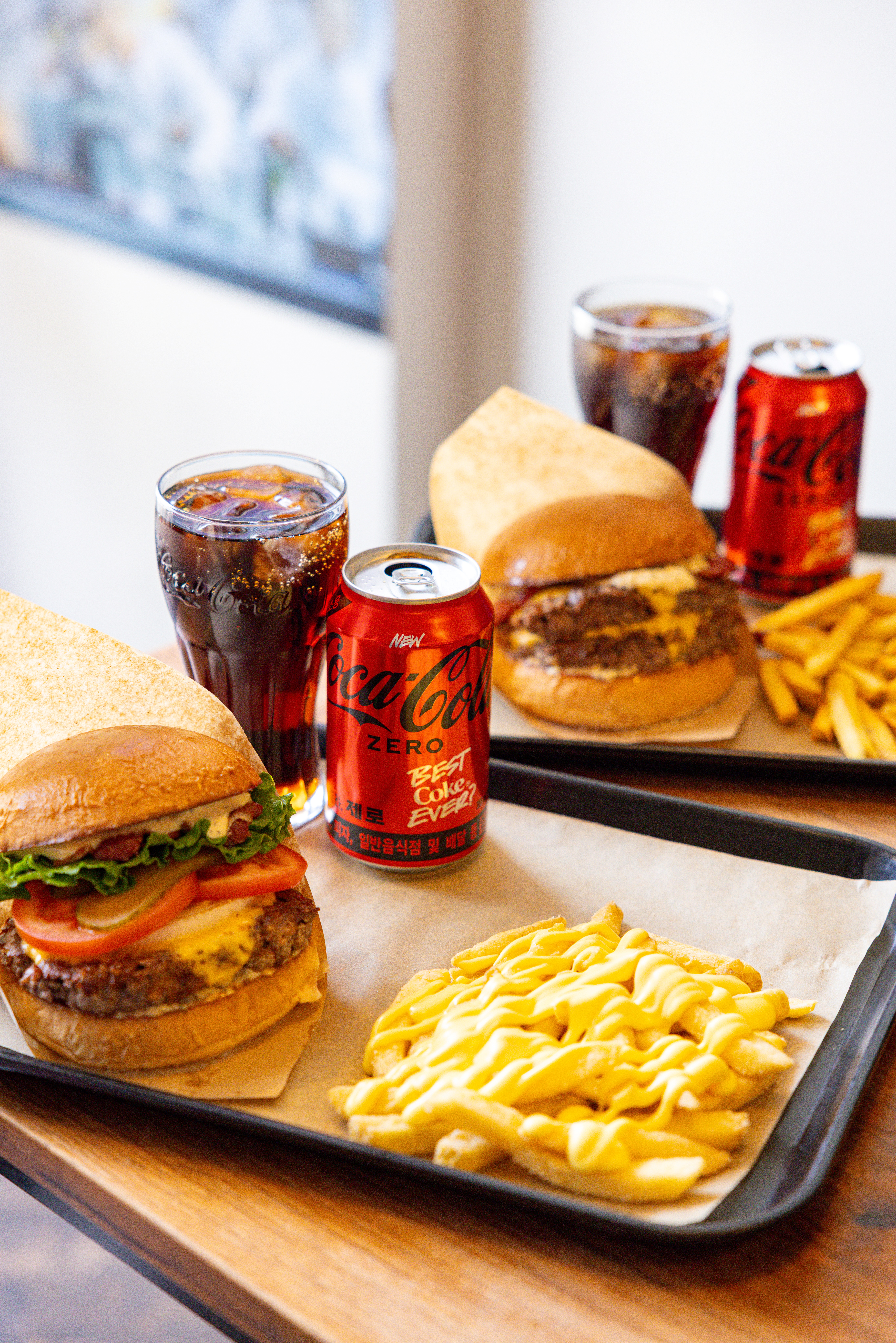 레드리본 맛집 '래빗홀버거컴퍼니'의 대표메뉴, 클래식 버거 세트와 더더블버거 세트를 코카-콜라 제로와 함께 즐기고 있다.