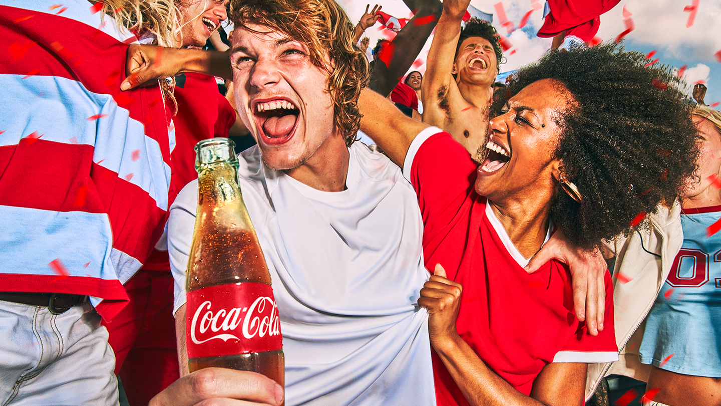 코카-콜라를 들고 월드컵 경기를 직관하며 열정적으로 응원하는 축구 팬들의 모습. 