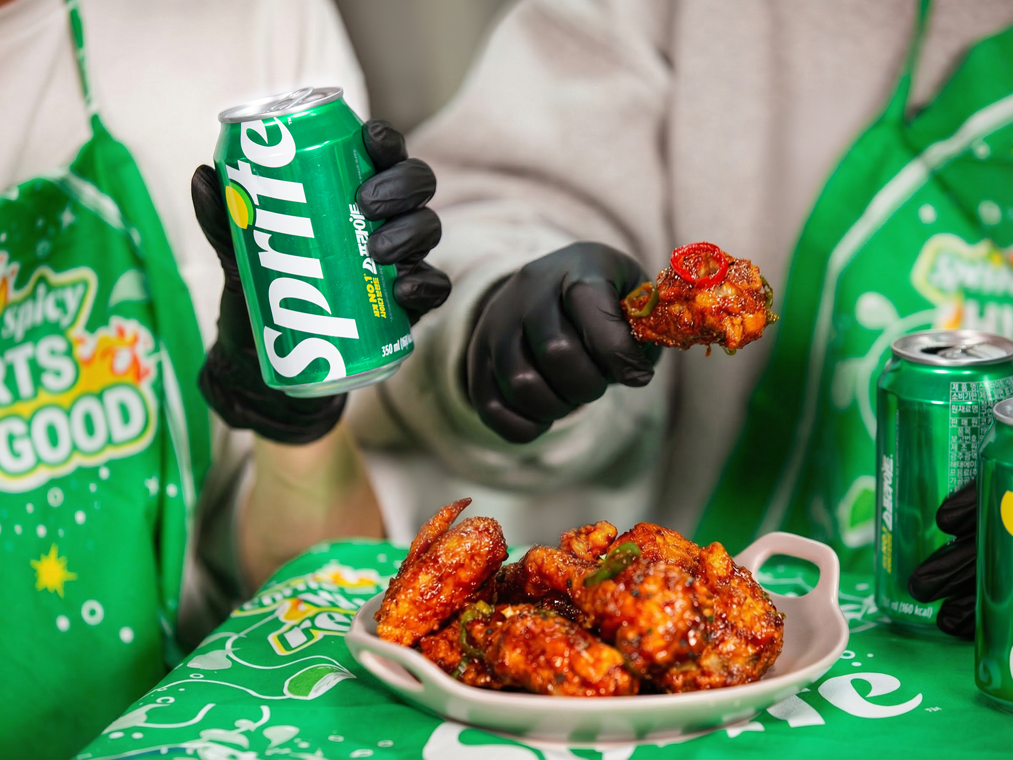 스프라이트 앞치마를 매고 스프라이트와 매운 양념 치킨을 함께 즐기고 있는 이미지.