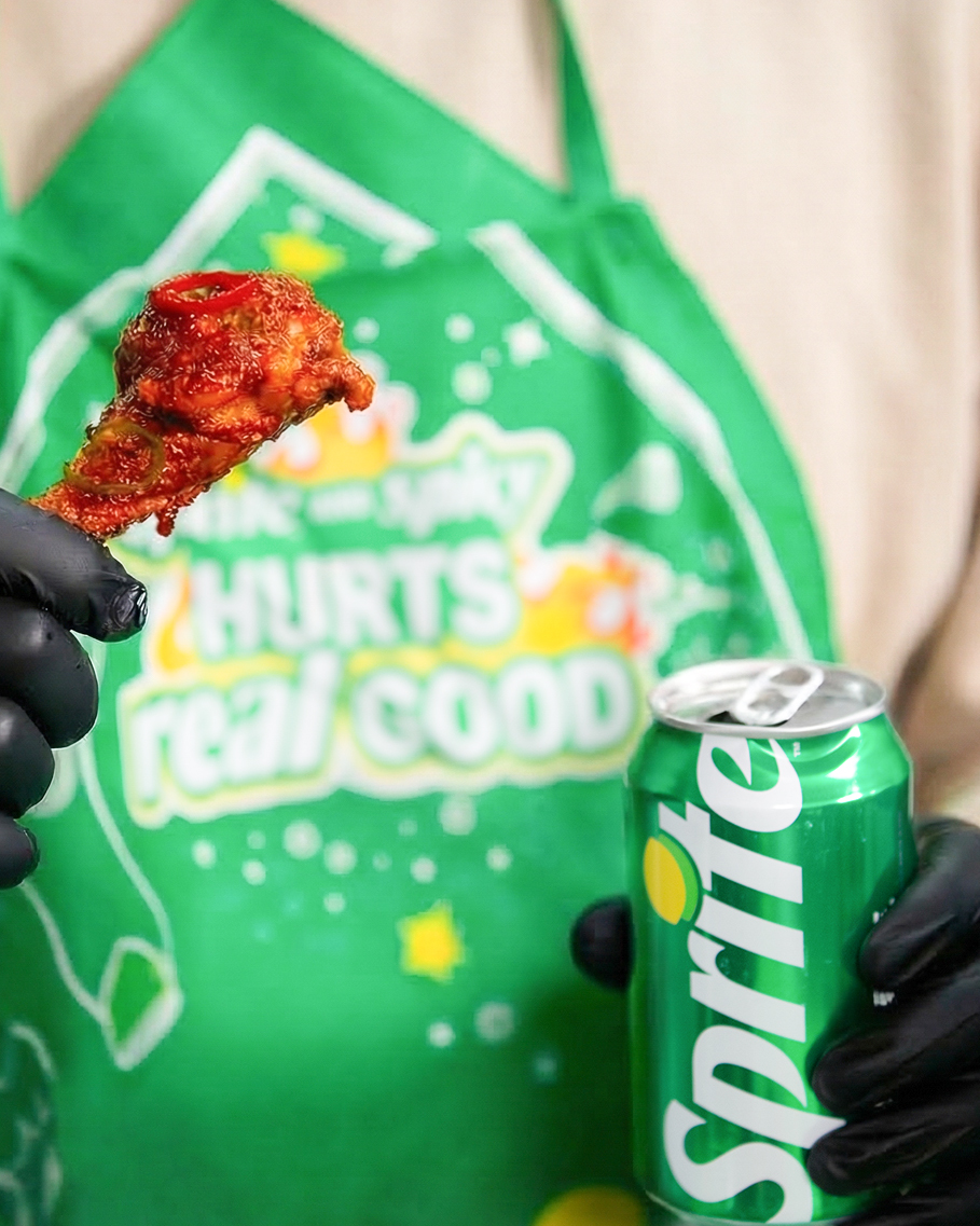 스프라이트 앞치마를 매고 스프라이트와 매운 양념 치킨을 함께 즐기고 있는 이미지.