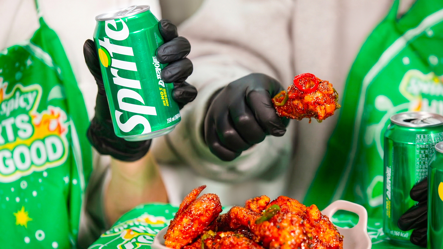 스프라이트 앞치마를 매고 스프라이트와 매운 양념 치킨을 함께 즐기고 있는 이미지.