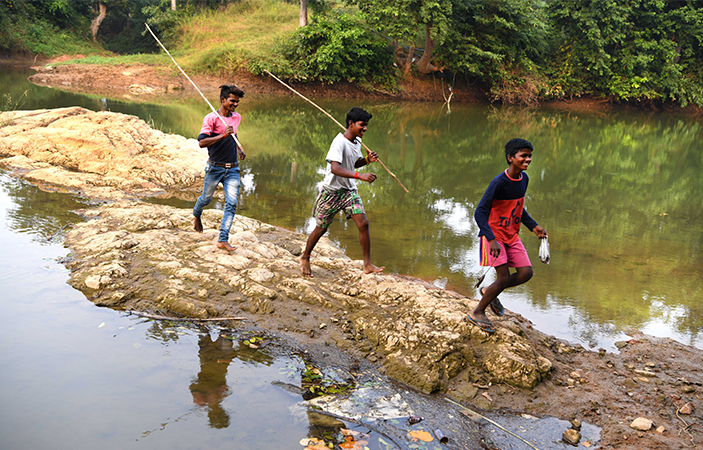 Three boys walking across a river bank