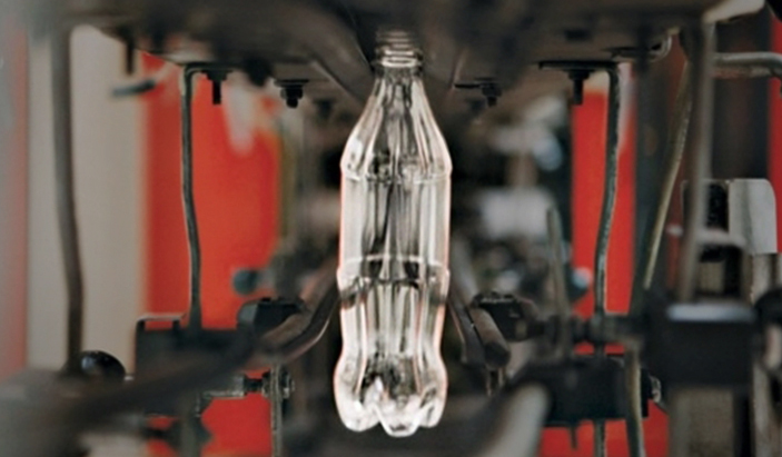 A clear glass bottle on a factory line.