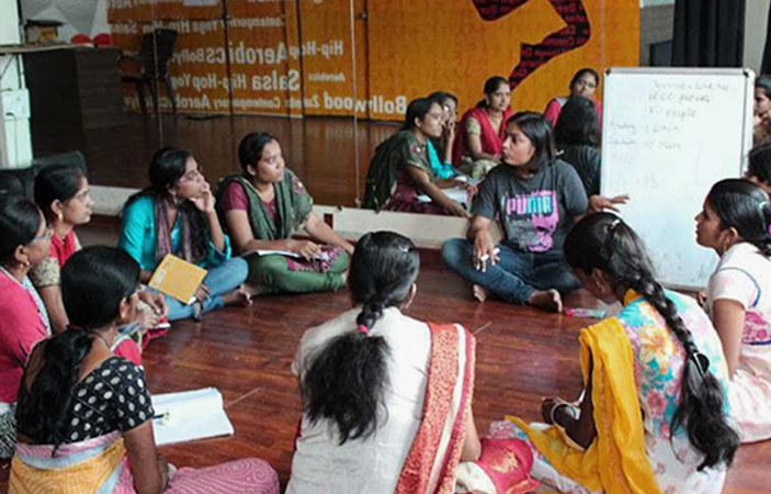 A group of women sat around a white board taking notes.