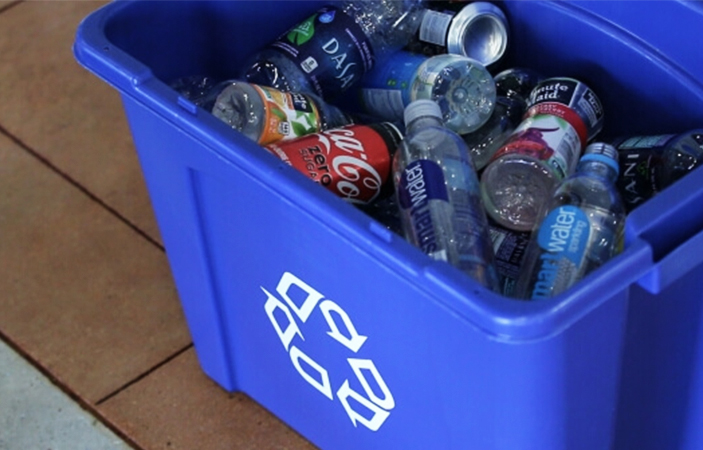 A blue recycling box full of empty drinks cans and bottles.