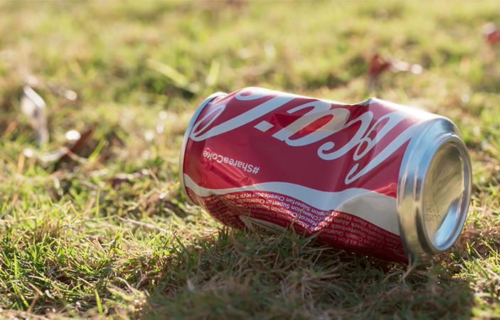 A crumpled coca cola can on grass.